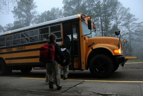 Kids being picked up for school by a bus on a foggy day